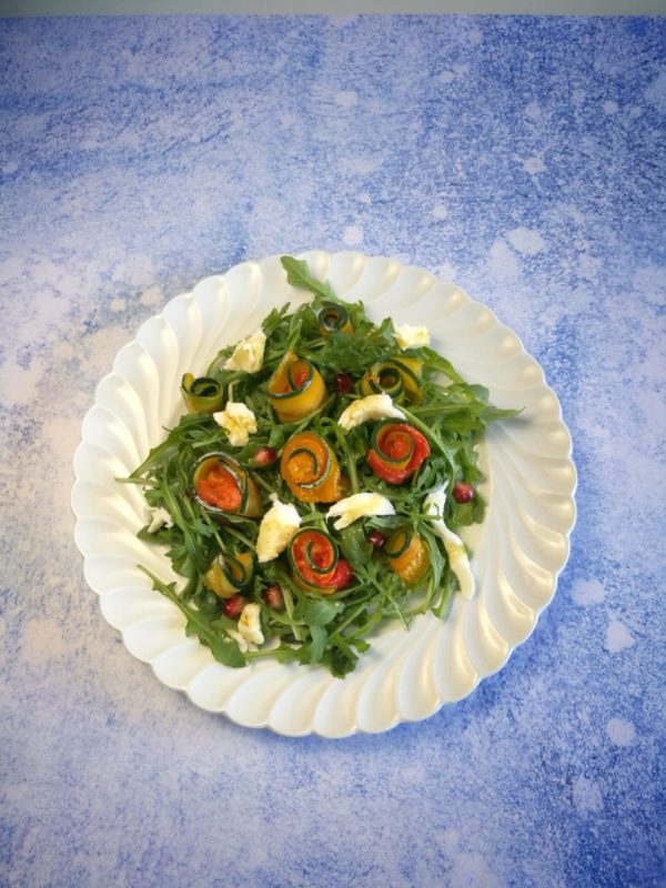 Salade de courgettes marinées au safran et roulées avec des poivrons sur lit de roquette avec mozzarella